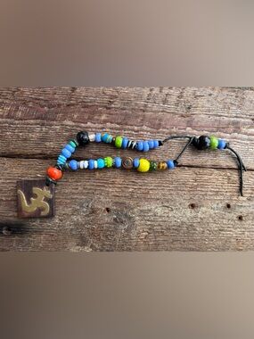 Handmade Glass Beaded.… whatever you want it to be. 
OM wood and brass pendant!